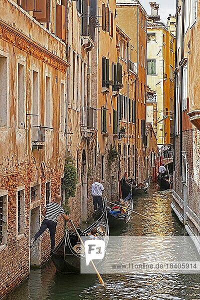 Gondoliere in traditionellen Gondeln  die Touristen auf Sightseeing Touren durch die engen Kanäle in Venedig  Venetien  Nordostitalien  mitnehmen