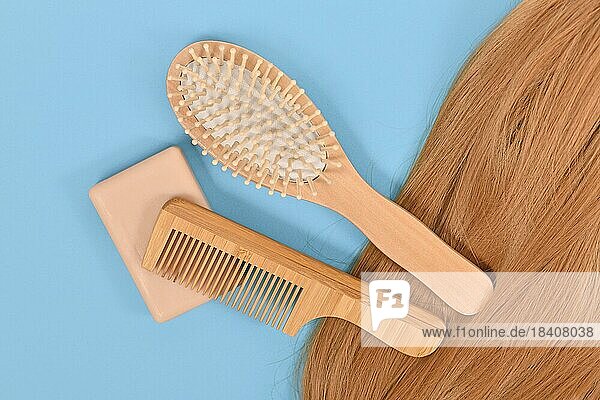 Gesunde Haarpflege Routine mit umweltfreundlichen festen Shampoo bar  Holzkamm und Bürste auf blauem Hintergrund