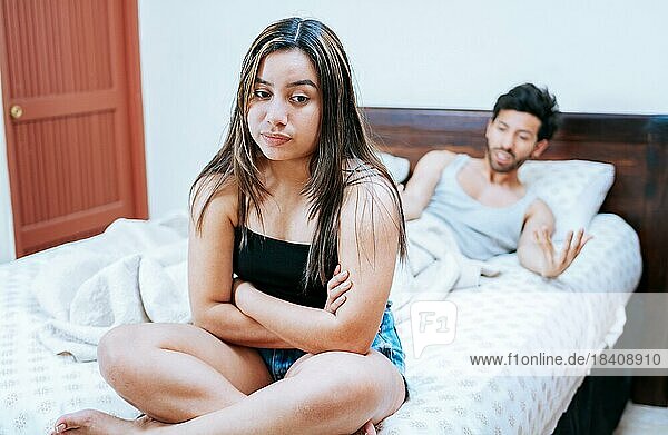 Wife arguing with her husband in bed. Young couple arguing sitting on the bed. Concept of couple problems in bed. Upset woman with husband sitting on bed
