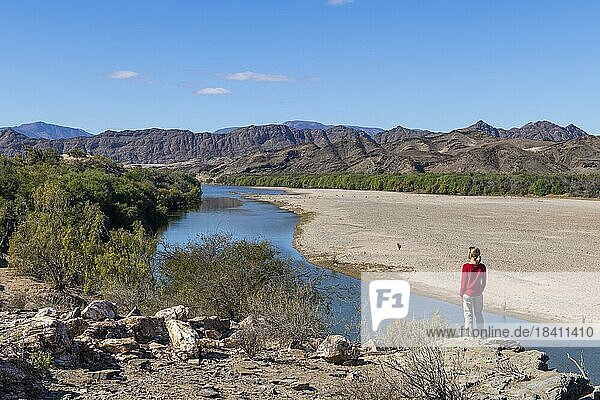 Frau steht am Orange River  auch Oranje-Fluss  an der Grenze zwischen Namibia und Südafrika  Oranjemund  Sperrgebiet Nationalpark  auch Tsau ?Khaeb Nationalpark  Namibia  Afrika