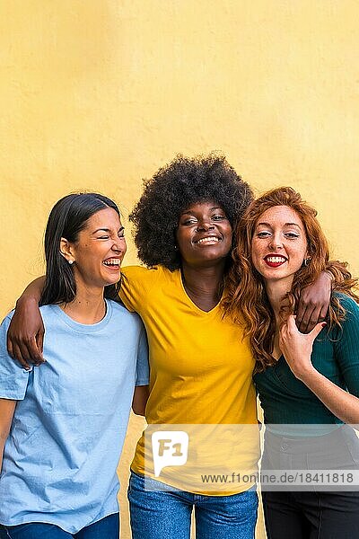 Porträt von schönen multiethnischen Freundinnen  die auf einer gelben Wand lächelnd Spaß haben  Copy Paste