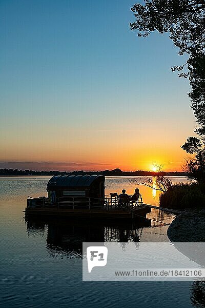 Zwei Männer sitzen bei Sonnenuntergang auf einem Hausboot  Hausfloß  vor der Insel Kiehnwerder  Breitlingsee  Brandenburg an der Havel  Havelland  Brandenburg  Deutschland  Europa