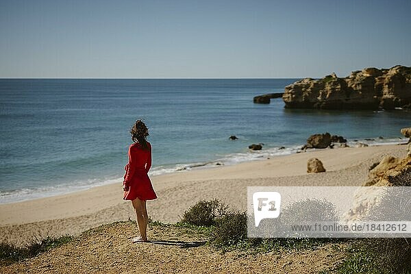 Attractive woman in red dress on top of cliffs at Sao Rafael Beach  Algarve coast  Portugal  Europe