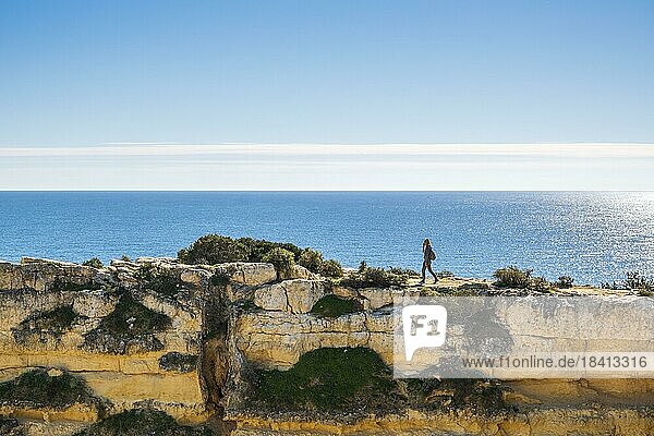 Eine Frau auf der Spitze der Klippen am Strand von Marinha in der Algarve  Südportugal