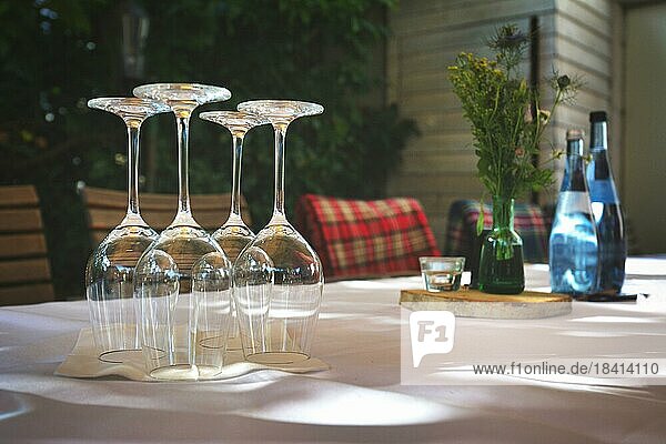 Elegante Tabelle im Restaurant mit angeordneten leeren Weingläser auf den Kopf gestellt und verschwommenen Hintergrund mit Wasserflaschen  Tischdekoration und Stühle mit Decken