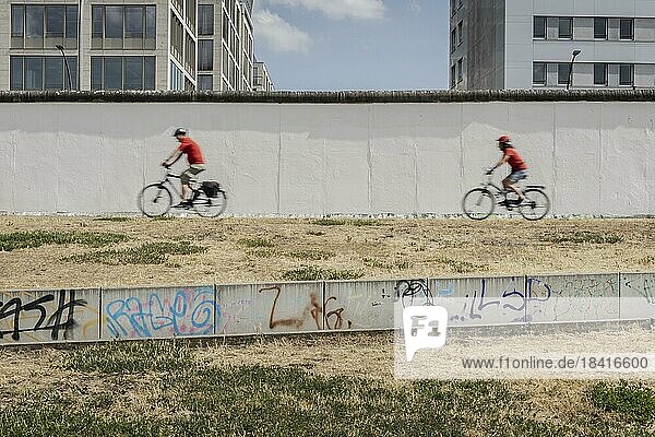 Zwei Radfahrer an der Berliner Mauer zeichnet sich ab an der East Side Gallery in Berlin  26.06.2022.  Berlin  Deutschland  Europa