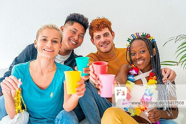 Lgtb Paare von Homosexuell Jungen und Mädchen lesbisch in einem Porträt auf einem Sofa in einem Haus Partei  Geburtstagsfeier  Toast mit farbigen Gläsern