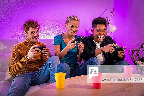 Eine Gruppe junger Freunde spielt zu Hause auf dem Sofa Videospiele  lila angeführt