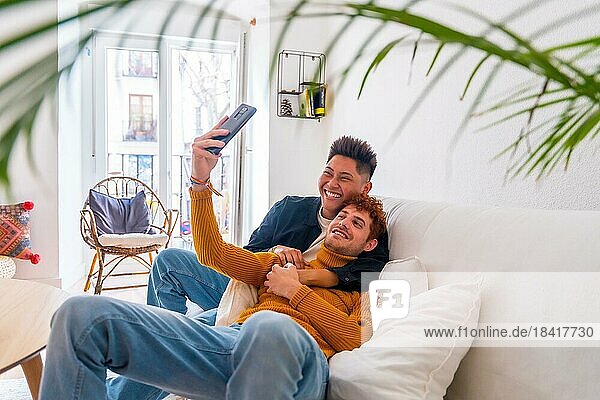 Schöne Homosexuell Paar wird romantisch drinnen zu Hause auf dem Sofa  ein Selfie  lgbt Konzept