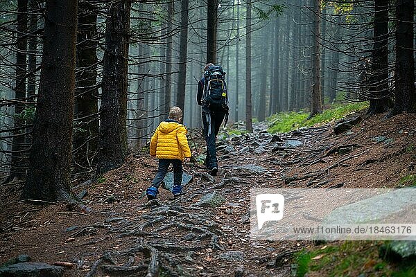 Eine Mutter und ihr kleiner Sohn gehen bei nassem Herbstwetter auf einen Bergpfad. Polnische Berge  Polen  Europa