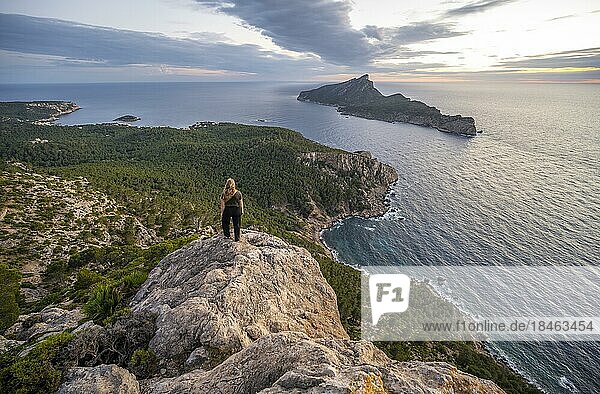 Junge Wanderin steht an Felsenküste mit einer Insel  Sonnenuntergang über dem Meer  Mirador Jose Sastre  Insel Sa Dragenora  Mallorca  Spanien  Europa
