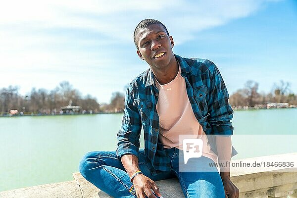 Portrait of a black ethnic man in summer by a city lake  enjoying vacation