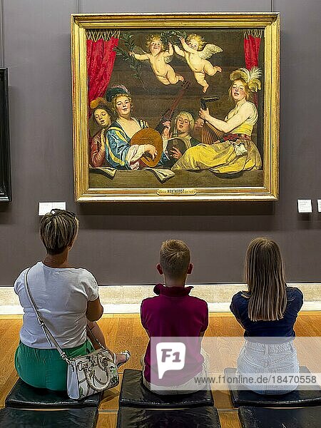 Eine Frau und zwei Kinder betrachten mit dem Rücken zum Fotografen ein Bild an einer Wand im Louvre  Paris  Frankreich  Europa