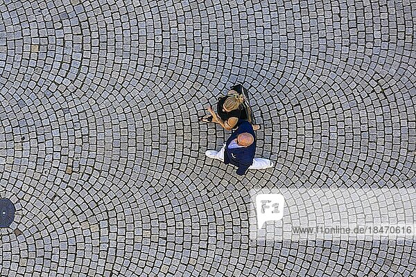 Zwei Personen  Mann und Frau  aus der Vogelperspektive  Menschen gehen über einen Platz mit Pflastersteinen  Symbolfoto  Stuttgart  Baden-Württemberg  Deutschland  Europa