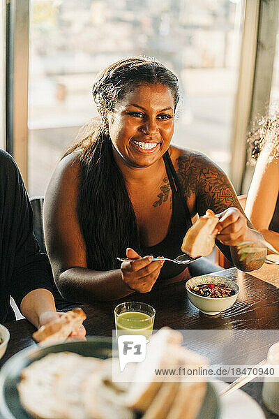 Lächelnde Frau beim Frühstück am Esstisch in einem Rückzugszentrum