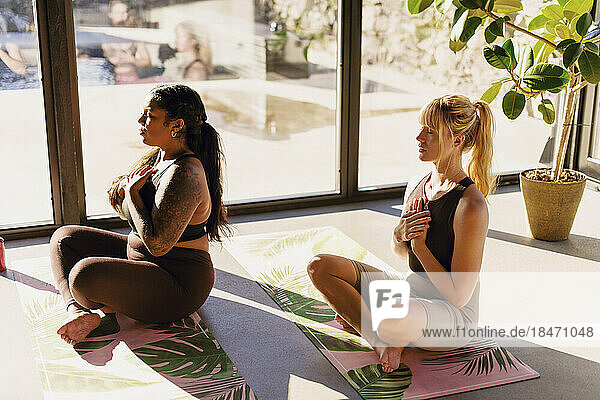 Frauen machen Atemübungen  während sie auf Übungsmatten im Rückzugszentrum sitzen