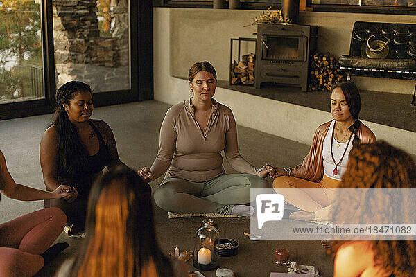 Multirassische Freundinnen halten sich an den Händen  während sie im Retreat Center meditieren