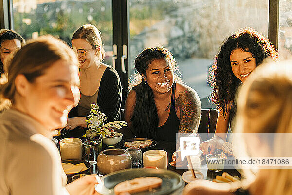 Fröhliche Frau unterhält sich mit Freundinnen beim Frühstück im Freizeitzentrum