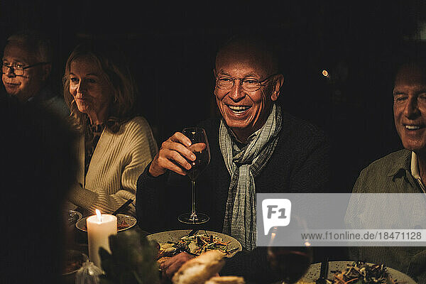 Happy senior man with friends during dinner party at night