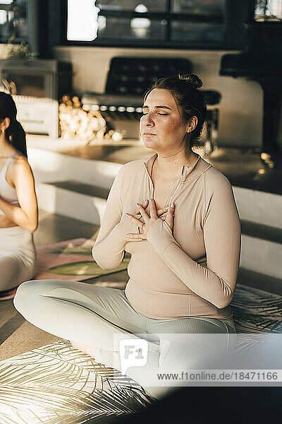 Frau meditiert mit den Händen auf der Brust im Schneidersitz im Retreat Center