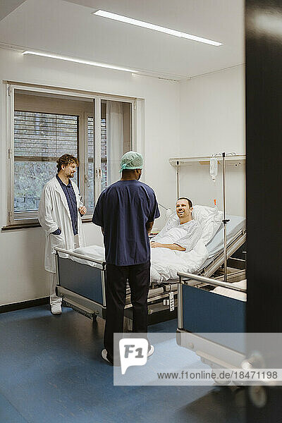 Smiling male patient talking to healthcare workers in hospital