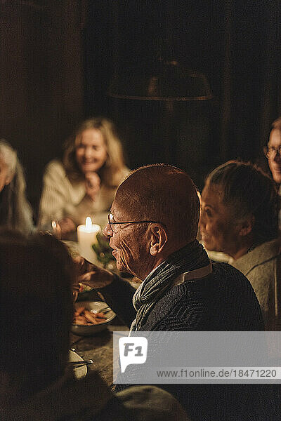 Älterer Mann mit Freunden bei einem Abendessen bei Kerzenschein