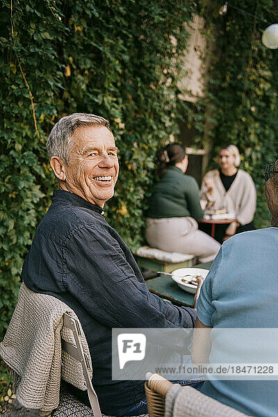 Happy senior man sitting on chair at restaurant