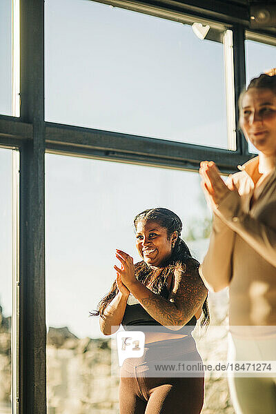 Glückliche Frauen klatschen während einer Yogastunde im Retreat Center