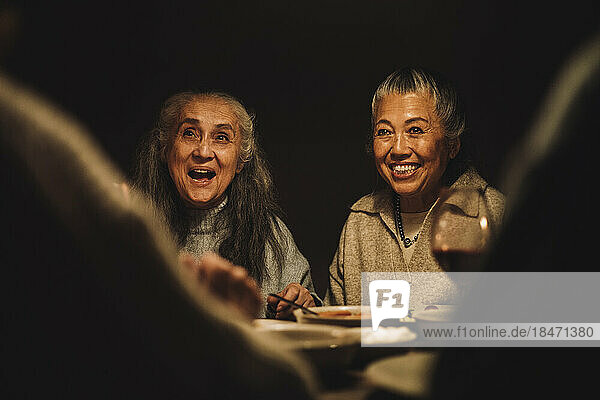 Glückliche ältere weibliche Freunde während einer nächtlichen Dinnerparty
