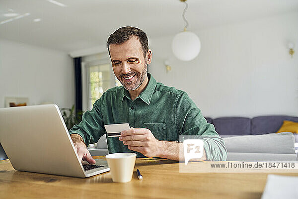 Man paying with credit card on his laptop sitting at desk