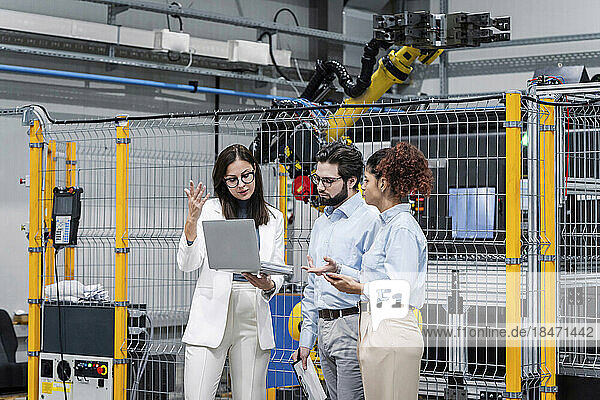 Businesswoman discussing over laptop with colleagues in factory