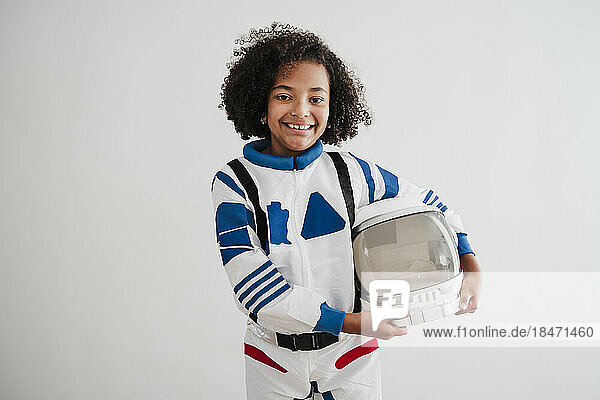 Smiling girl wearing space suit standing in front of white wall