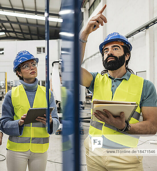 Engineer gesturing colleague in factory