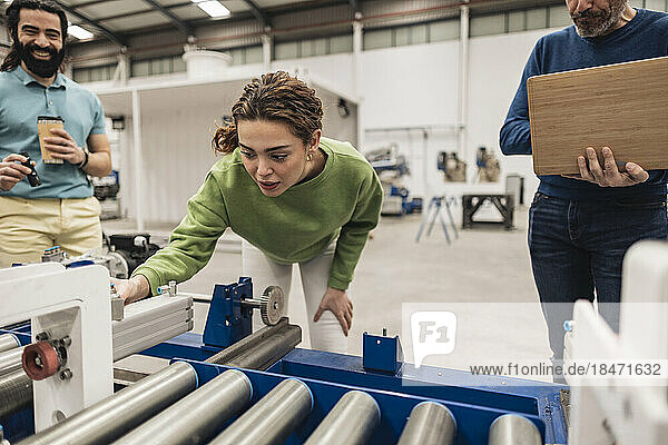 Engineer analyzing conveyor belt with colleagues in robotics factory