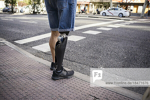 Man with prosthetic leg waiting at roadside