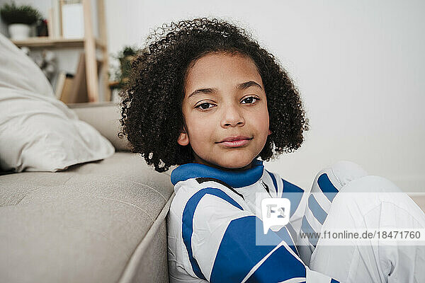Girl with curly hair wearing space suit at home