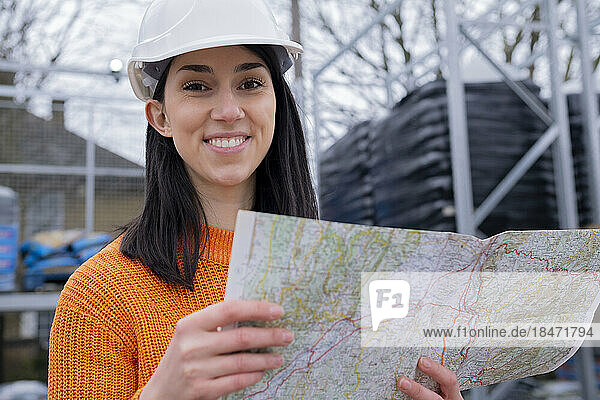 Smiling young woman with map at site