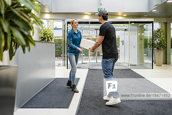 Delivery person giving box to customer in office lobby