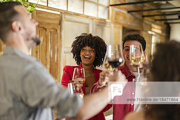 Happy friends toasting wineglasses celebrating at restaurant