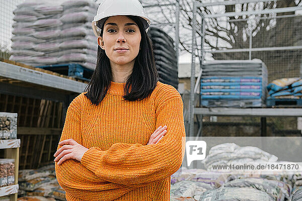 Selbstbewusste junge Frau steht mit verschränkten Armen auf der Baustelle