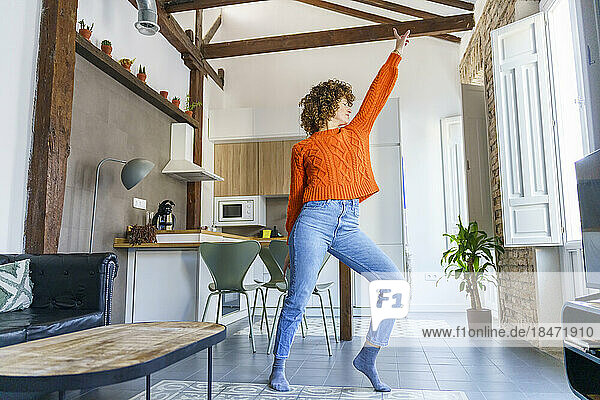 Woman with curly hair dancing at home
