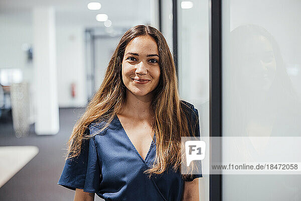 Smiling businesswoman with long hair standing in office