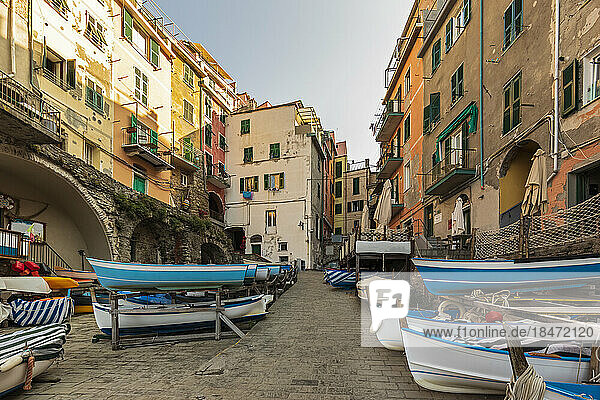 Italy  Liguria  Riomaggiore  Boats lying along empty street of coastal town along Cinque Terre