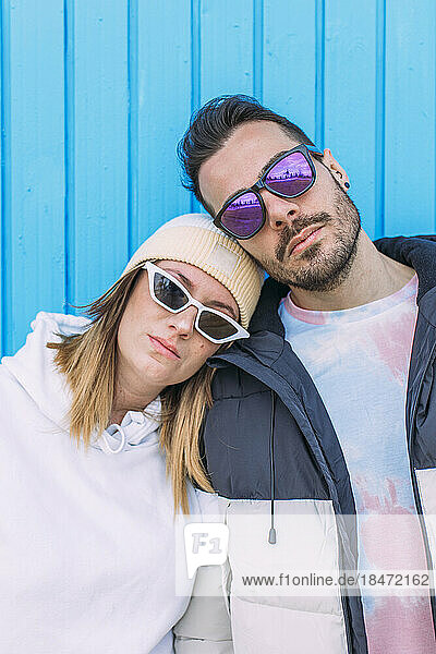 Man and woman wearing sunglasses in front of wall