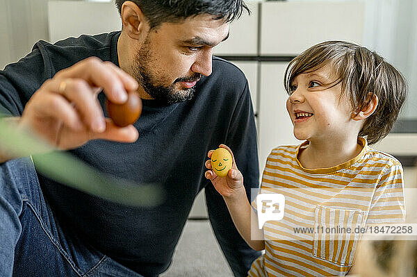 Father and son holding decorated eggs for Easter at home
