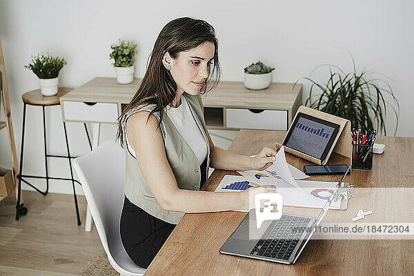 Geschäftsfrau macht sich im Büro Notizen vom Laptop