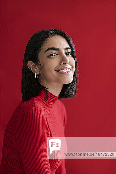 Smiling young woman against red background