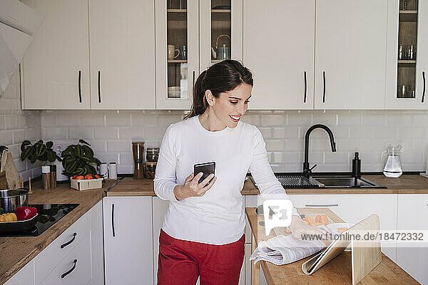 Glückliche Frau benutzt Tablet-PC in der Küche