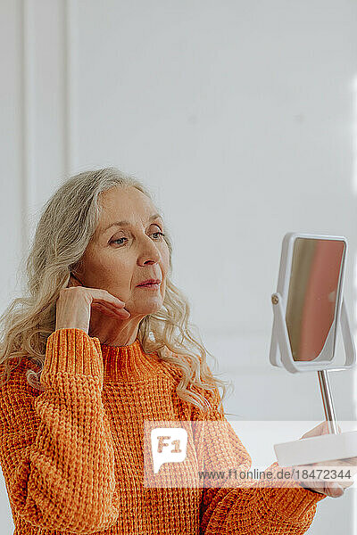 Senior woman looking in mirror at home