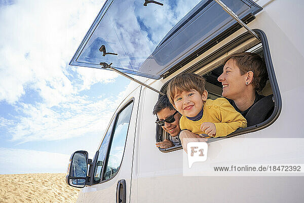 Glücklicher Sohn und Eltern schauen durch das Fenster eines Wohnmobils in die Wüste